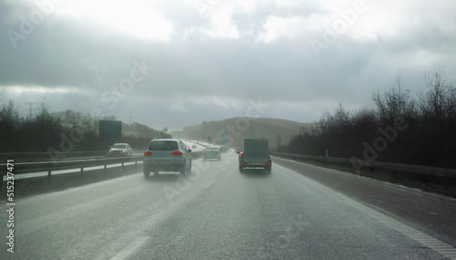 Cars driving on a wet and rainy day. Staying safe and avoiding accidents on a highway. Asphalt road through the countryside on a cold and misty day, surrounded by trees and open grassland in Germany