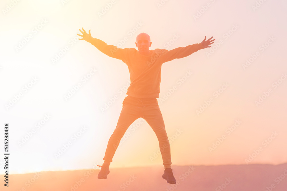 Young athletic man jumping high during sunset