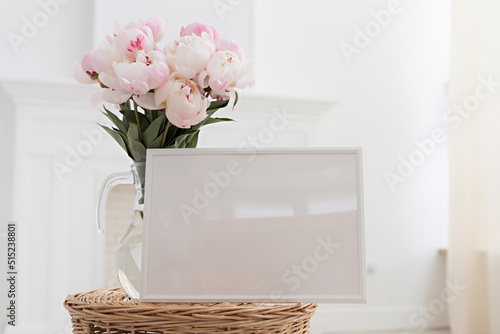 Horisontal frame mockup. Glass vase with a bouquet of pink peonies. Modern fireplace in a Scandinavian interior.