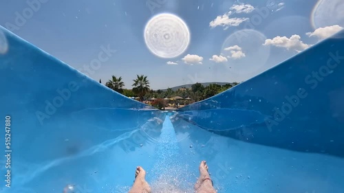 European girl going of a blue waterslide in the summer