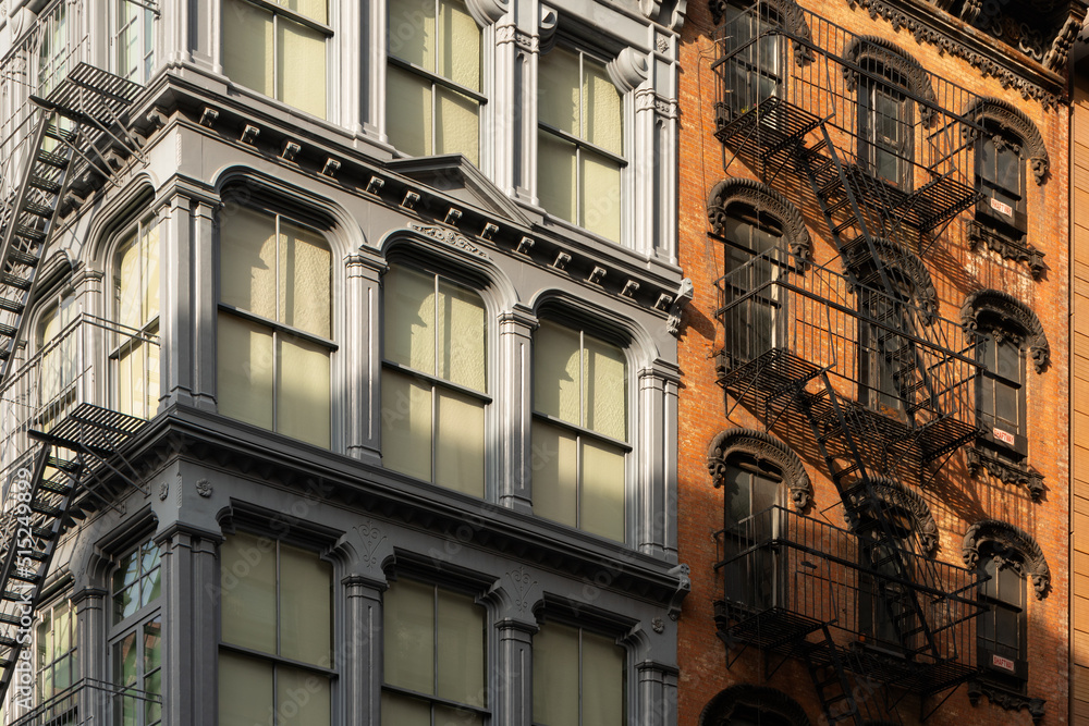 Cast iron and brick facades of Soho loft buildings with fire escapes at sunset. Soho Cast Iron Building Historic District, Lower Manhattan, New York City