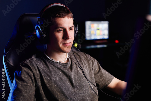 Portrait of Caucasian young man playing video games in dark and speaking into headset