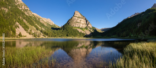 Lac des Sagnes in Summer with La Tour des Sagnes pyramid-shaped mountain in the Mercantour National Park (panoramic) at sunset. Jausiers, Ubaye Valley, Alpes de Haute Provence, Alps, France photo