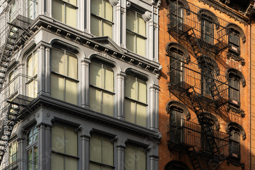 Cast iron and brick facades of Soho loft buildings with fire escapes at sunset. Soho Cast Iron Building Historic District, Lower Manhattan, New York City