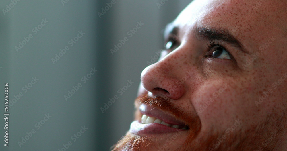 Obraz premium Man opening eyes looking up smiling, close-up redhead face man looks up