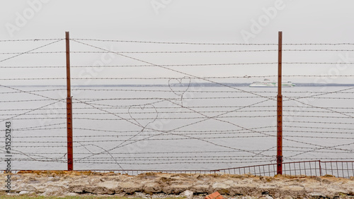 Heart shapes in rusty barbed wire, selective focus with blurry sea and coast in the background. Detail of Patarei, abandoned soviet prison in Tallinn, Estonia  photo