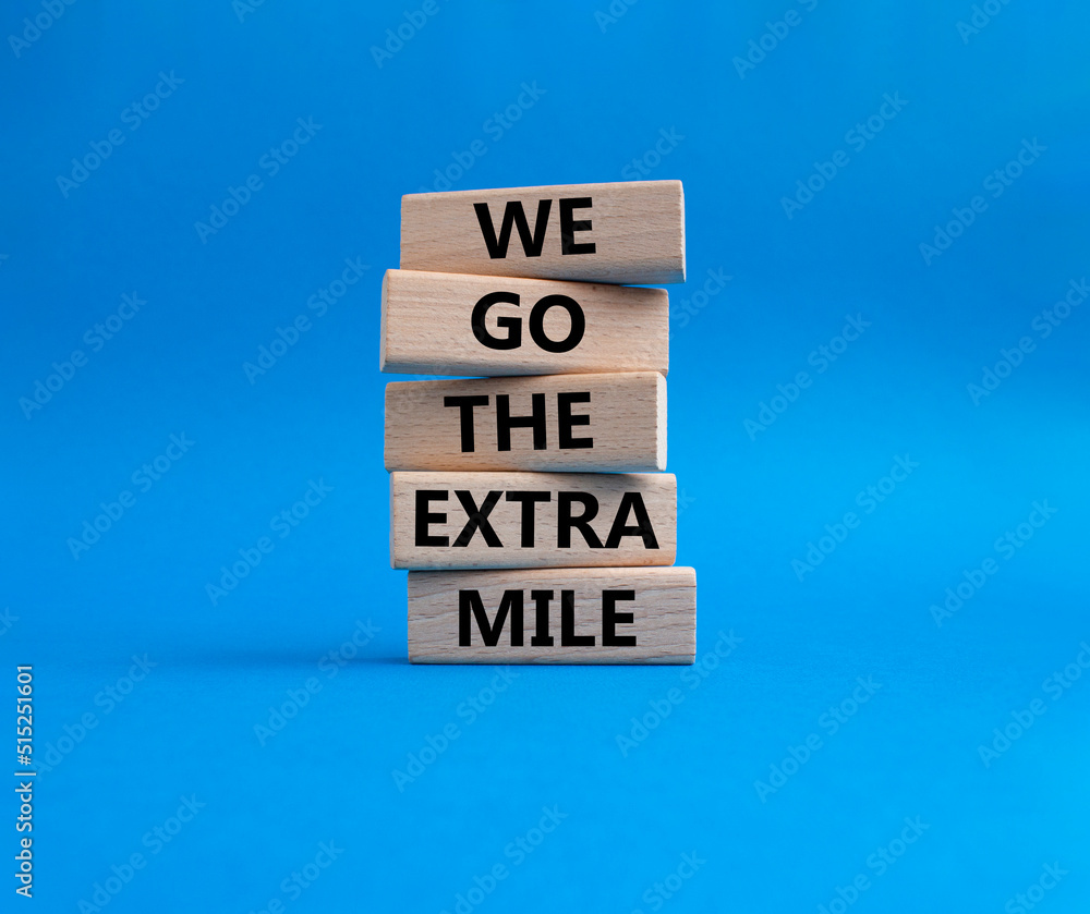 We go the extra mile symbol. Wooden blocks with words 'We go the extra mile'. Beautiful blue background. Business and 'We go the extra mile' concept. Copy space. We go the extra mile symbol. Wooden blocks with words 'We go the extra mile'. Beautiful blue background. Business and 'We go the extra mile' concept. Copy space.