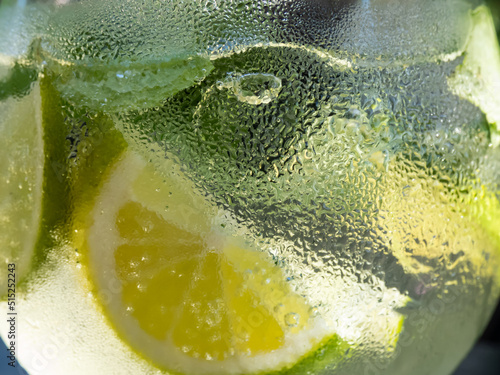 Macro shot of Coctail Mojito with green mint leaves, white rum, lime, lemon, soda and ice cubes. Beautiful macro shot of mojito cocktail glass covered with condenstion photo