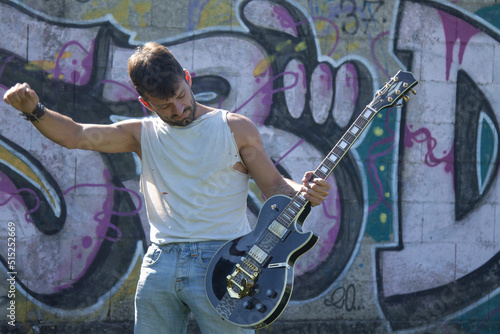 young man playing electric guitar on graffiti wall