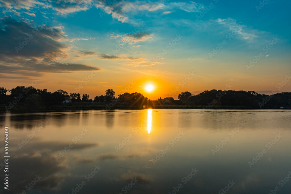 Beautiful rising sun over Odra river full of reflections in water and cloudy sky