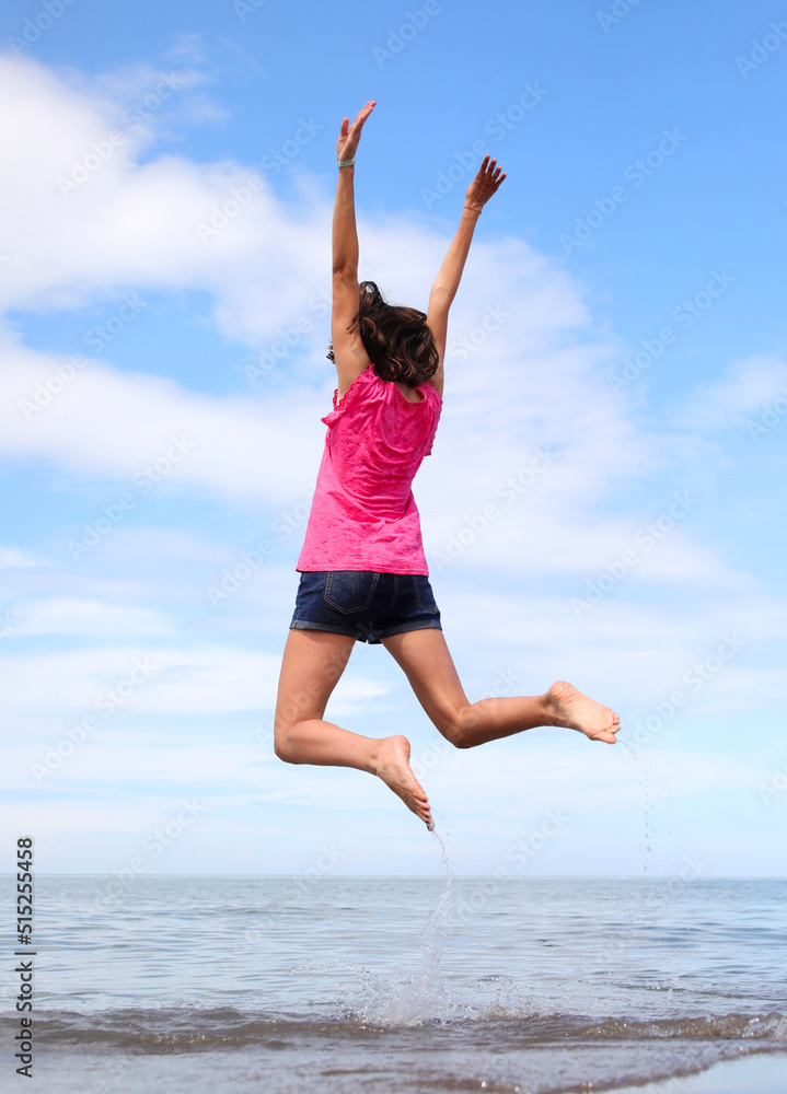 young girl while doing gymnastic exercises and jumping very high near the sea young girl while doing gymnastic exercises and jumping very high near the sea
