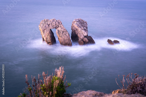 Long exposure view of the beautiful seascape with the spectacular rock formations near the coast in the Cantabrian sea, Urro of the apple tree in Costa Quebrada at sunset, Liencres, Cantabria, Spain photo