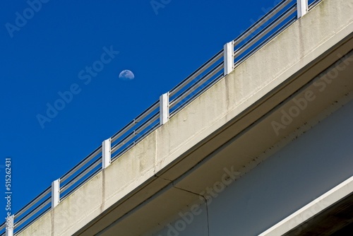 'Waxing gibbous moon over causeway bridge in afternoon sunlight'
