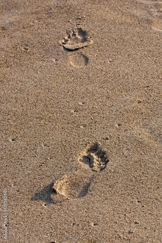  Barefoot tracks on sandy beach in late afternoon sun 