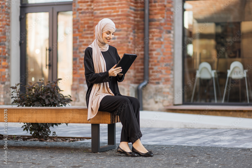 Pretty smiling muslim business woman in hijab sitting on bench and ...