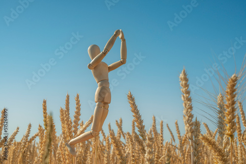 Prayer for Ukraine. The wooden figurine of a man cries out to God against the background of the sky and wheat ears.