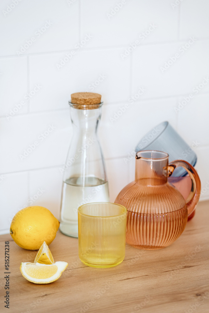 Jug of water, colored transparent glasses and lemon Jug of water, colored transparent glasses and lemon