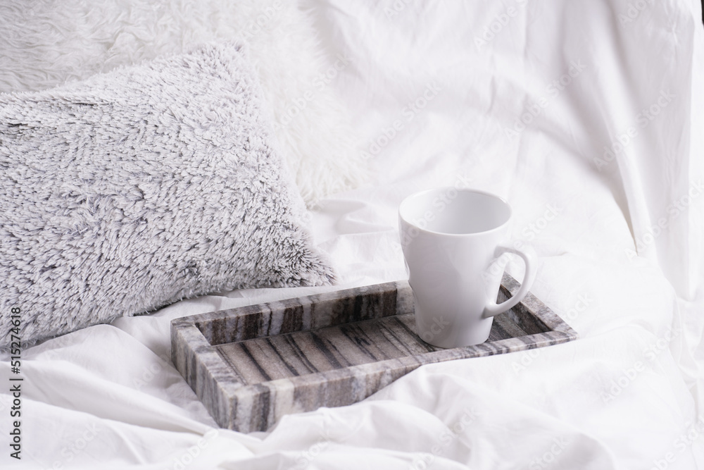 an empty white porcelain cup for coffee or tea in grey marble tray on white bed sheets among fluffy pillows - breakfast in bed an empty white porcelain cup for coffee or tea in grey marble tray on white bed sheets among fluffy pillows - breakfast in bed