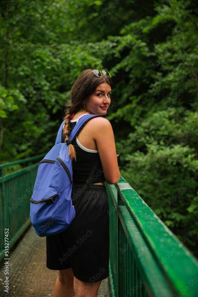 Hiker looking at the camera while crossing a bridge in mountains Hiker looking at the camera while crossing a bridge in mountains