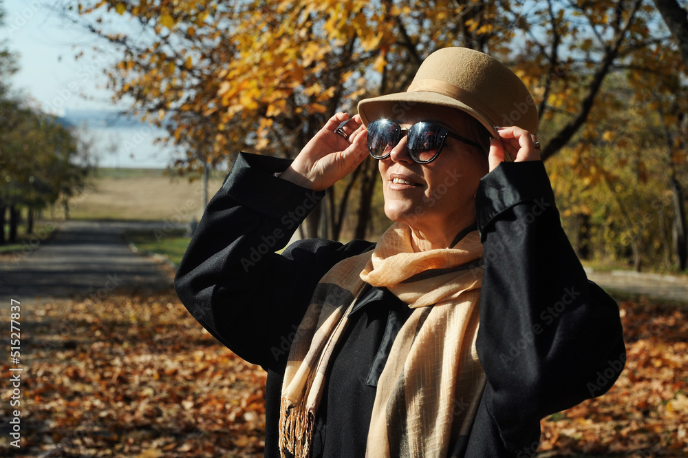 Middle aged beautiful woman outdoors. Mature beautiful woman walking in autumn park. Middle aged beautiful woman outdoors. Mature beautiful woman walking in autumn park.