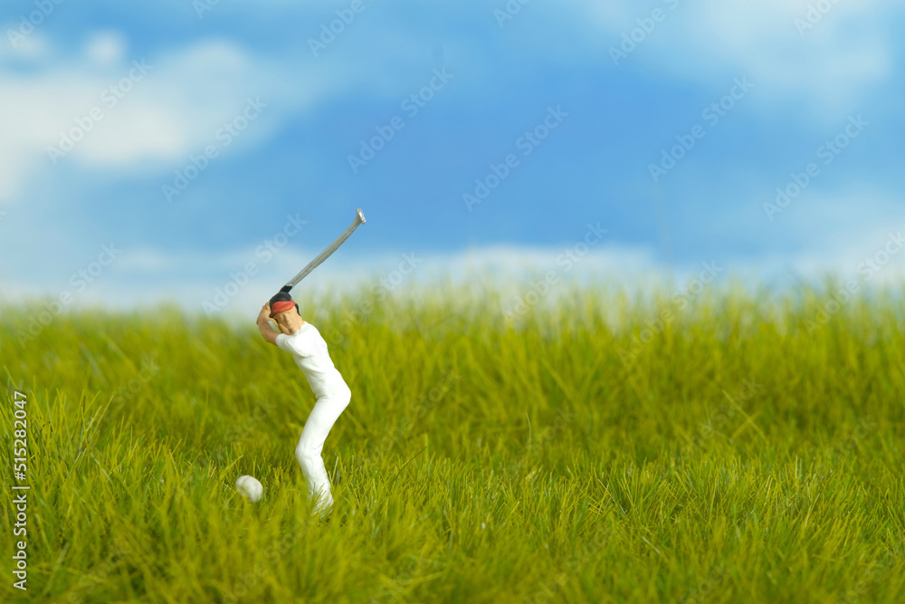 Miniature people toy figure photography. A girl golfer try to shot the ball at meadow golf field on bright cloudy day morning Miniature people toy figure photography. A girl golfer try to shot the ball at meadow golf field on bright cloudy day morning