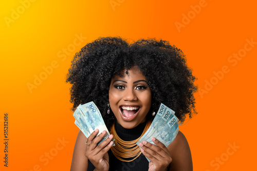 woman holding money, young smiling woman holding Brazilian money, orange gradient background