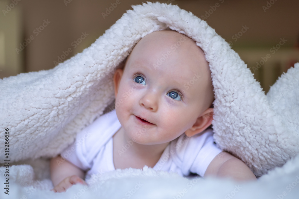 smiling baby looking at camera under a white blanket, towel. smiling baby looking at camera under a white blanket, towel.