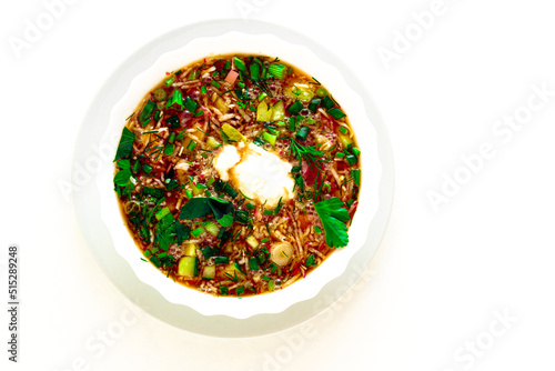 Traditional summer dish - cold borscht with potatoes egg, herbs, radish, cucumber, beetroot, sour cream. A dish of Ukrainian, Polish and Russian cuisine. White isolated background. photo