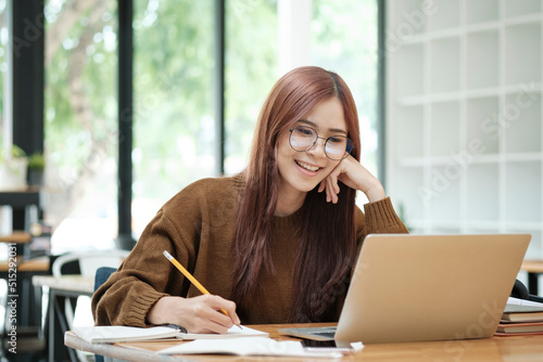 Young collage student using computer and mobile device studying online.