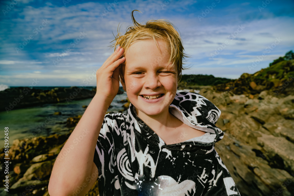 Boy wearing hooded towel after swimming being silly on rocks at The Tanks tourist attraction at Forster, NSW Australia