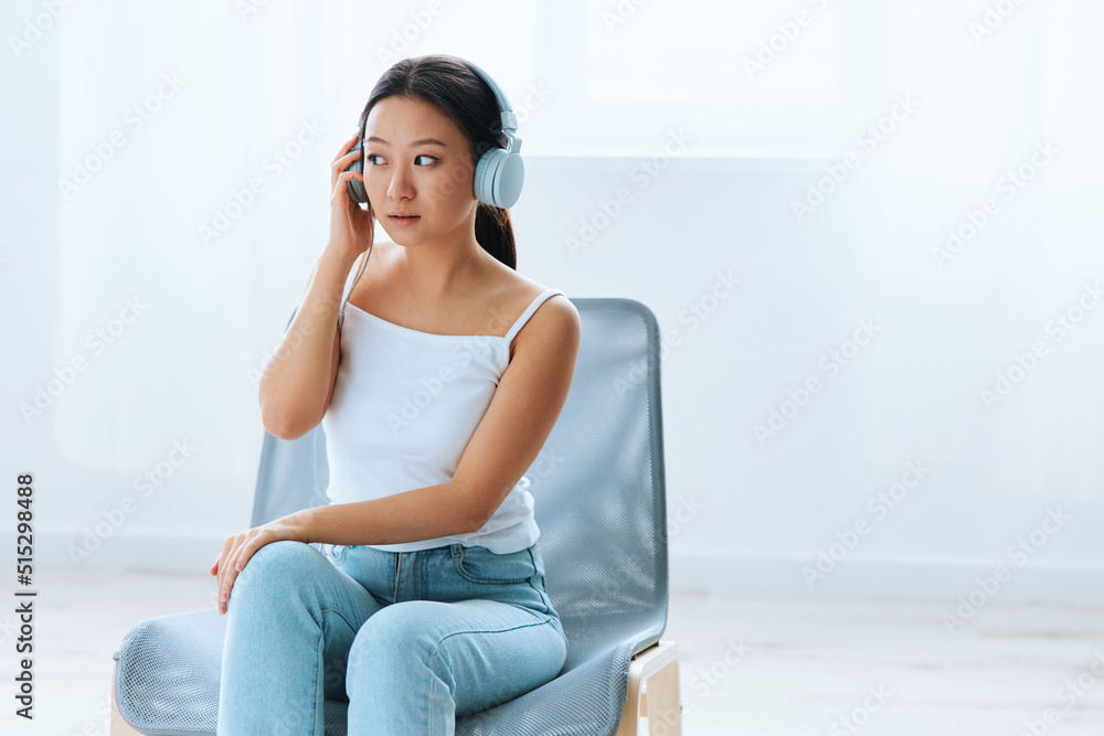 Excited shocked tanned lovely young Asian lady in headphones looks aside listens to external sounds at home interior living room. Sound Studio Stream Social media concept. Cool offer Banner Wide angle Excited shocked tanned lovely young Asian lady in headphones looks aside listens to external sounds at home interior living room. Sound Studio Stream Social media concept. Cool offer Banner Wide angle