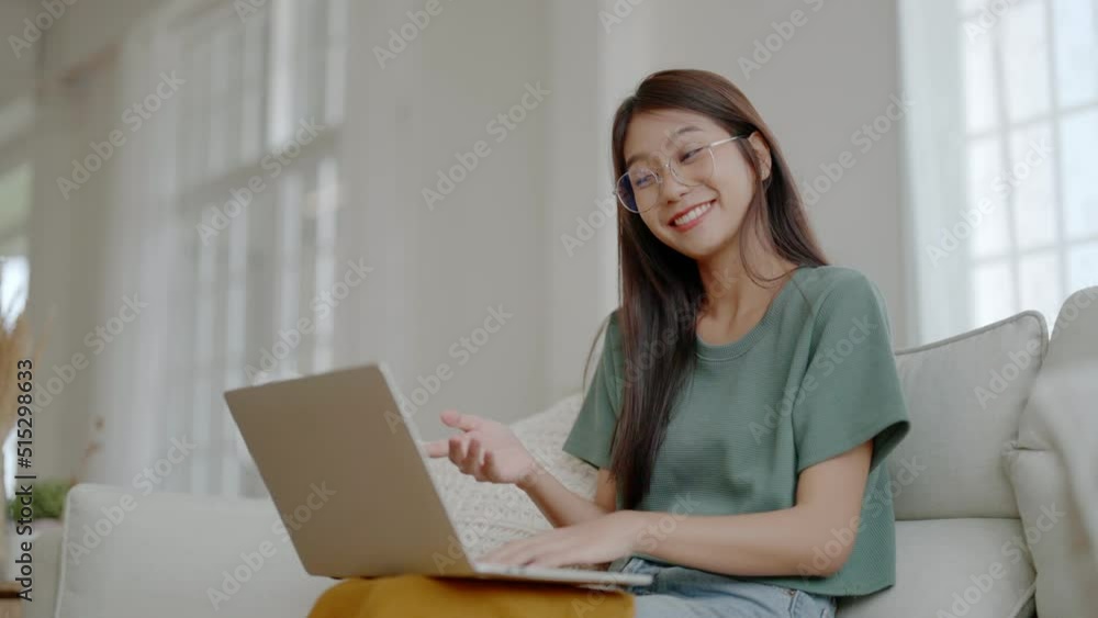 Smiling young asian woman working on laptop at home. Attractive asia female using computer remote studying, watching online education and video calling Smiling young asian woman working on laptop at home. Attractive asia female using computer remote studying, watching online education and video calling