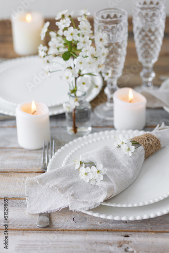 Rustic zero waste wedding decor with natural elements. Wooden table, candles, linen napkins, branches with green leaves. Eco-friendly decoration for the special dinner. Romantic and cozy place
