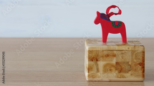 A Christmas tree toy in the form of a traditional Swedish dalahorse stands on a wooden Scandinavian juniper box.  photo