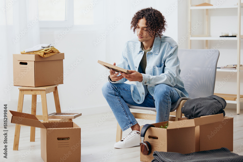 handsome guy unpacking things from boxes in the room sorting things out handsome guy unpacking things from boxes in the room sorting things out