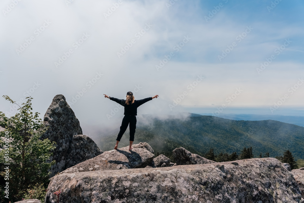 A girl on top of Mount Pidan looks at a beautiful mountain valley in the fog in summer. Travel and tourism. Hiking A girl on top of Mount Pidan looks at a beautiful mountain valley in the fog in summer. Travel and tourism. Hiking