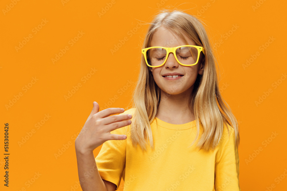 Naklejka premium portrait of a cute beautiful school-age girl in yellow glasses for vision on a yellow background, pleasantly smiling looking at the camera