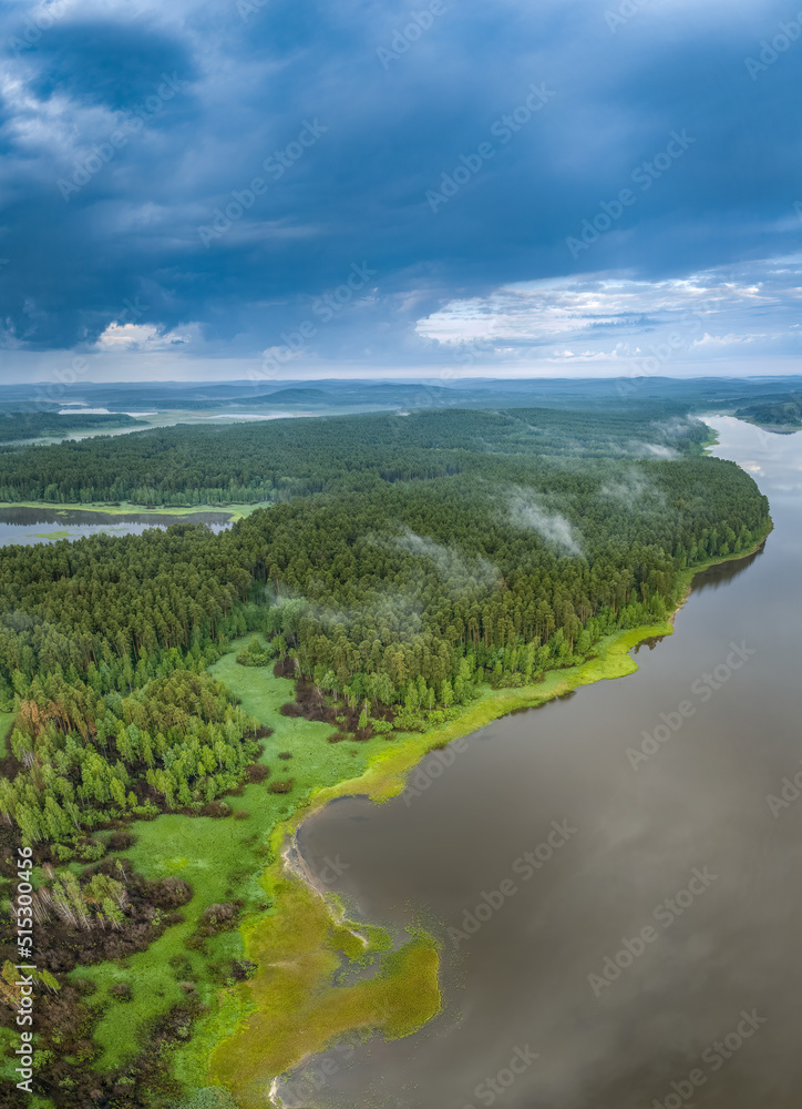 Big lake with green shores with morning fog in dawn, aerial landscape. Recreation concept. Aerial view