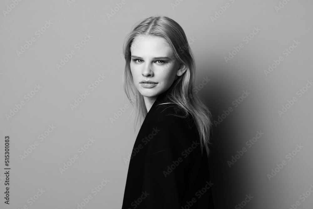 Fototapeta premium Young expressive beautiful blonde professional model posing isolated in studio dressing in black jacket looks at camera. Fashion Minimalistic concept