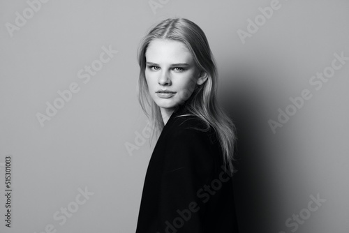 Young expressive beautiful blonde professional model posing isolated in studio dressing in black jacket looks at camera. Fashion Minimalistic concept
