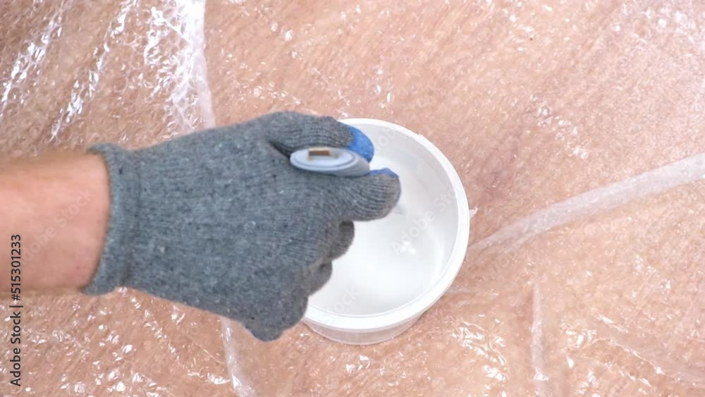 A man stirs white acrylic paint with a special plastic stirrer