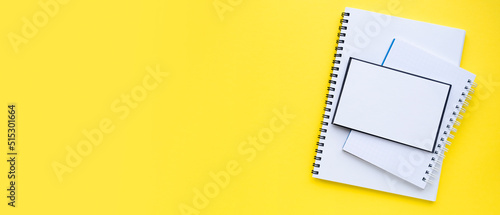 A stack of blocks and notebooks with a spiral. Bright yellow background. Banner. copyspace. Top view, flat lay. Back to school concept.