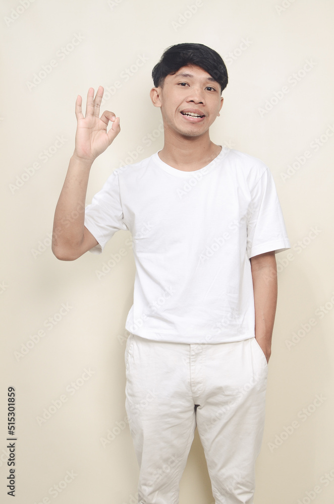 Asian man over isolated background surprised and showing OK sign Asian man over isolated background surprised and showing OK sign