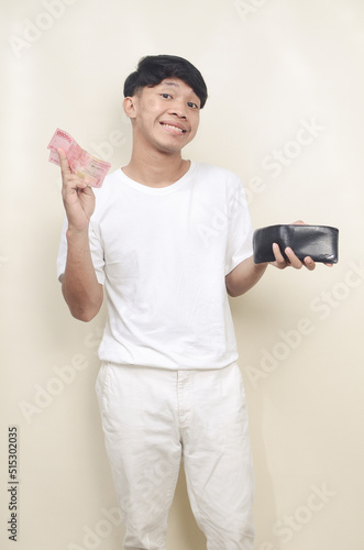 Asian man smiling to the camera while taking paper money from his wallet photo