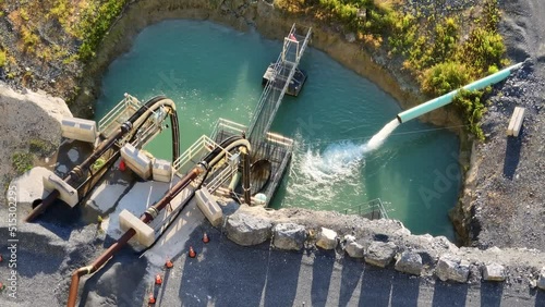 Flood water pump from quarry excavation into holding area. Mining theme. Aerial top down. Limestone rock quarry in USA.