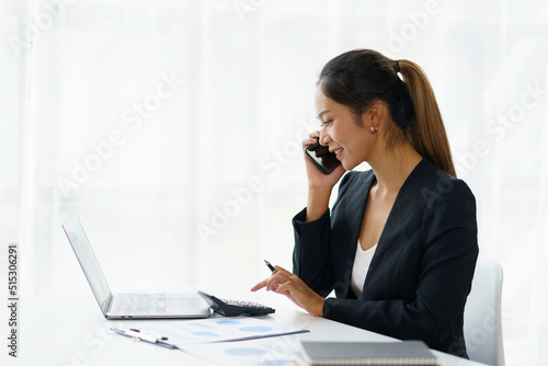 Asian businesswoman talking on the phone with customer in the office.