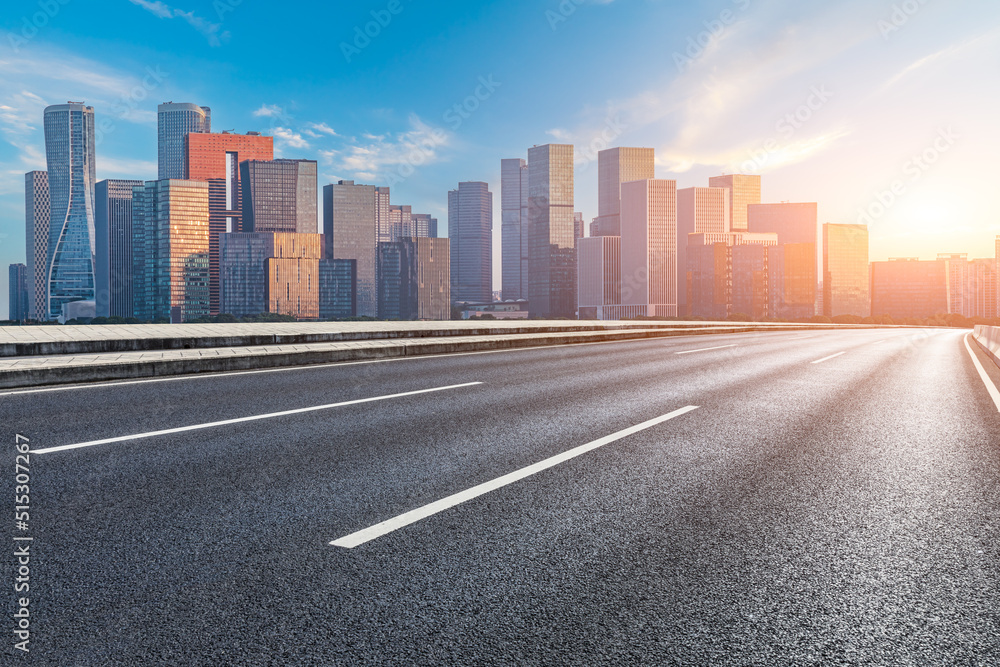 Asphalt road and modern city skyline with buildings in Hangzhou at sunset, China.