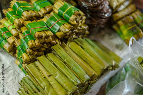 Suman or budbud, a rice cake wrapped in banana leaves, for sale in a public market. photo