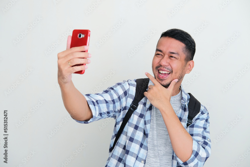 Adult Asian man taking a selfie photo with happy expression Adult Asian man taking a selfie photo with happy expression