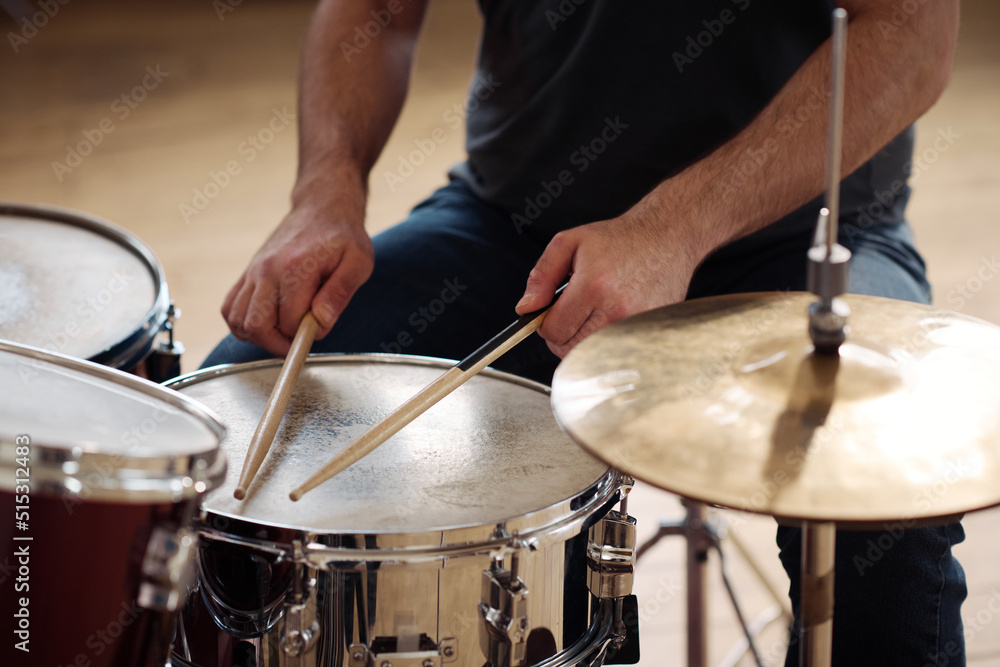Close-up of man sitting behind drum kit and playing drums during rehearsal Close-up of man sitting behind drum kit and playing drums during rehearsal